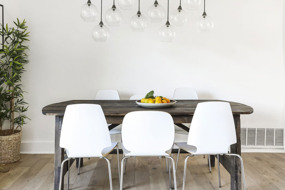Dining room of home on Sonata Lane featuring a table with white chairs and hanging lights